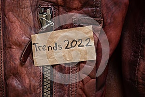 winter women's brown sheepskin coat as a background, natural winter coat and text on a piece of paper trends 2022