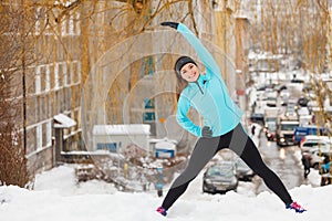 Winter workout. Girl wearing sportswear, stretching exercises.