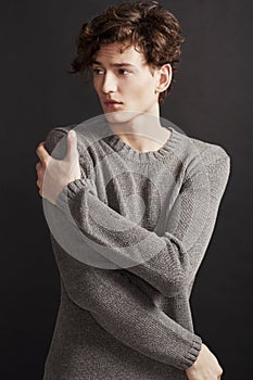 Winters chill - Fashion. A young man with elegant facial features wearing a woolen jersey and looking away thoughtfully.