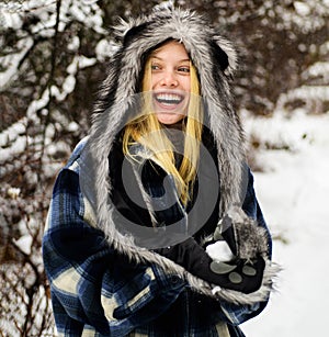 Wintertime. Happy woman in snowy winter park in warm wear with snowball in hands. Smiling winter girl playing with snow