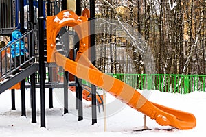 Wintertime. Little kid running upstairs to the slide on the play