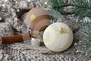 Wintertime spa set with bath bombs, fir tree branch over ligths on knitting plaid.