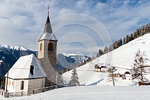 A wintertime view of a small church with a tall steeple