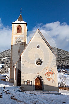 A wintertime view of a small church with a tall steeple