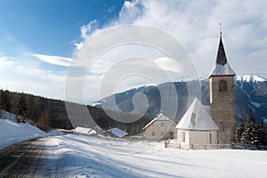 A wintertime view of a small church with a tall steeple