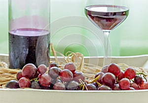 Winw bottle, glass of red wine and grapes on a rustic plate