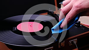 Wipe a vinyl record with a rag, dark background. Turn on the music