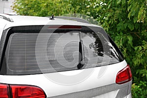 Wiper cleaning raindrops from car rear windshield outdoors