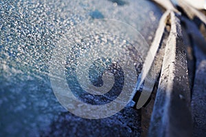 The wipers are covered with frost on the frozen glass of the car