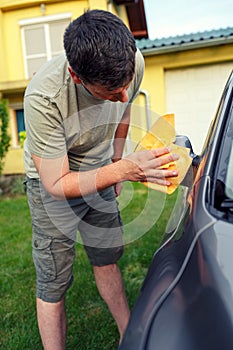 Wiping car- male cleaning car with microfiber cloth, car detailing.