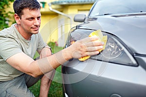 Wiping car- man cleaning car with microfiber cloth, car detailing in the house yard.