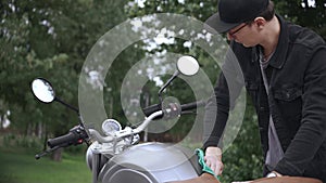 Wiping leather scrambler motorbike with cloth on the street after washing it