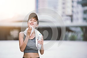 Wiping sweat Thirsty exercising female drinking fresh water after training