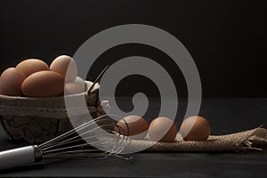 Wire basket with fresh eggs and fabric and whisk