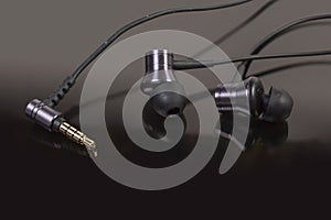 Wire in-ear earphones and audio plug on a dark surface