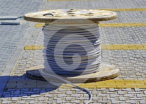 Wire electric cable with wooden coil of electric cable waiting to be slipped into the conduit
