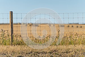 wire fence with farm fields behind it