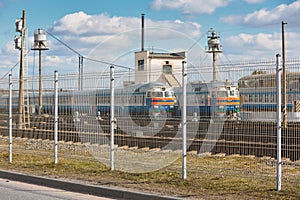 Wire fence restricting access to train depot with standing trains out of focus railway depot background. Concept of protecting
