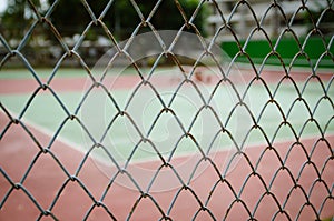 Wire fence with tennis court on background