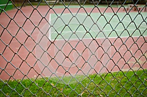 Wire fence with tennis court on background