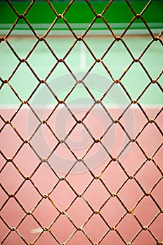 Wire fence with tennis court on background