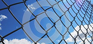 Wire fence with white clouds and blue sky background
