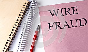 WIRE FRAUD word on the pink paper with office tools on white background