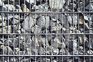 Wire Gabion Rock Fence. Stone wall texture, rocks behind metal grid fence background.
