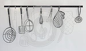 Wire kitchen utensils hang on the white wall