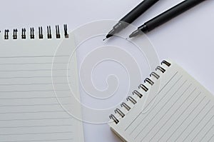 Wirebound Notebook and Black Pens On White Background.