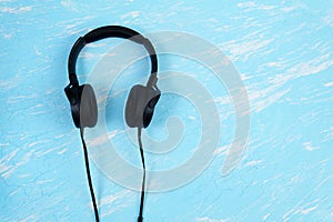 Wired black headphones on a blue background. The view from the top. Flatlay. copyspace