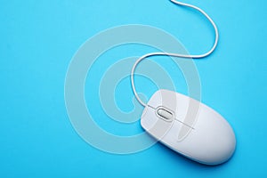 Wired computer mouse on blue background, top view. Space for text