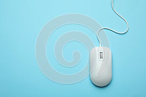 Wired computer mouse on light blue background. Space for text