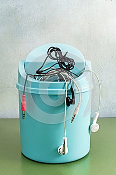 Wired headphones in a plastic office trash can