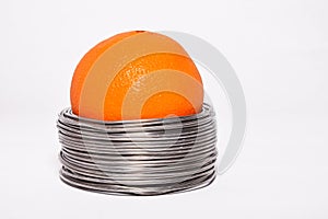 Wired orange: whole orange in coils of aluminium wire isolated o