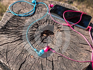 Wired pink and blue in-ear headset plugged in to the phone