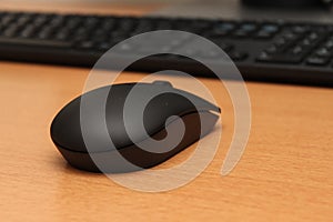 Wireless black stylish computer mouse lying on table.