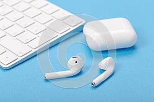 Wireless bluetooth earphones with charging case on a blue background. The concept of modern technology