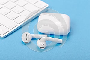 Wireless bluetooth earphones with charging case on a blue background. The concept of modern technology