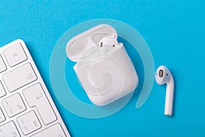 Wireless bluetooth headphones with charging case on a blue background. The concept of modern technology