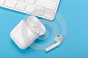 Wireless bluetooth headphones with charging case on a blue background. The concept of modern technology