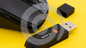 Wireless computer mouse with wifi adapter on yellow background.