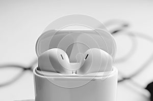 Wireless ear buds in glossy white plastic case. Close-up, selective focus. Place for text, copyspace
