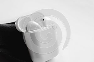 Wireless ear buds in glossy white plastic case on white background, close-up. Place for text, copyspace