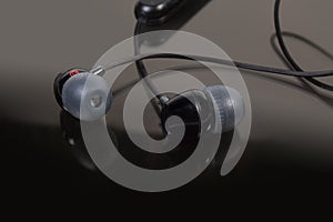 Wireless in-ear earphones with volume control on dark surface
