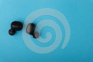 Wireless earbuds or earphones on blue background. Copy space