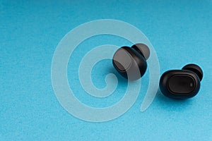 Wireless earbuds or earphones on blue background. Copy space