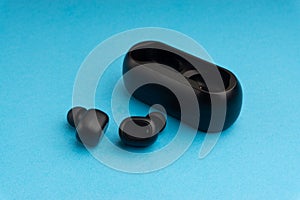 Wireless earbuds or earphones on blue background. Copy space