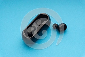 Wireless earbuds or earphones on blue background. Copy space