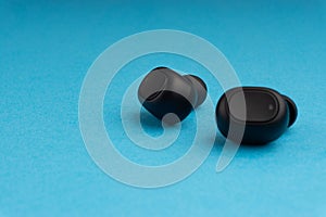 Wireless earbuds or earphones on blue background. Copy space